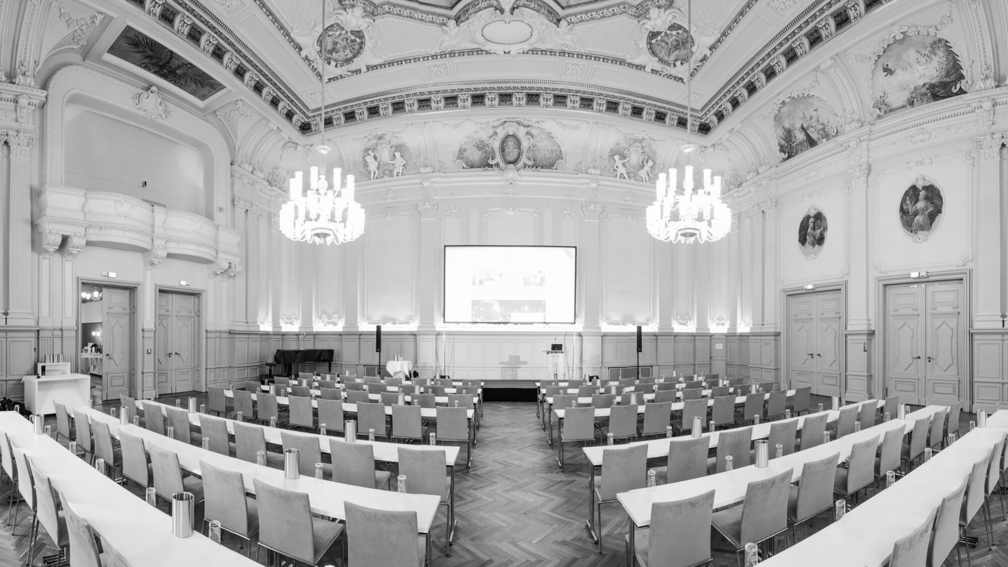 Partnerkongress - Ein großer Raum mit Stühlen und einer Projektionsleinwand, ideal für Präsentationen und Versammlungen.